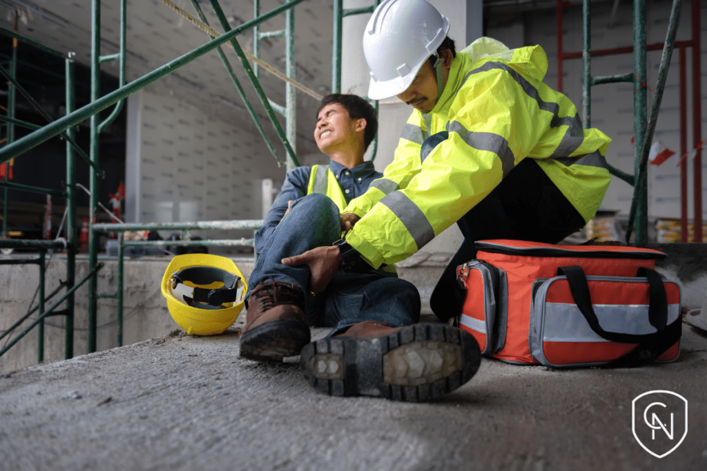 The image depicts a construction site accident where a worker has fallen from scaffolding.