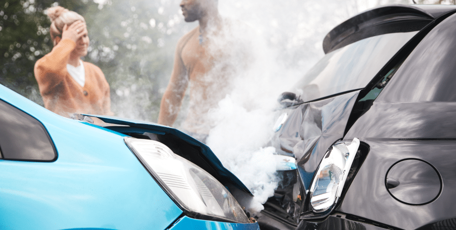 Woman, holding her head, and a man who got into a car accident talking behind the damaged, smoking cars