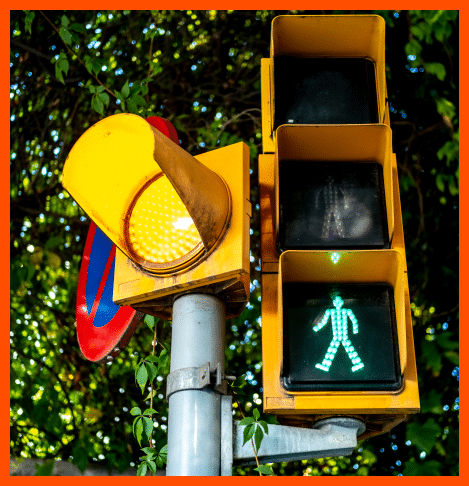 Traffic and pedestrian light with the bottom, green pedestrian indicating it is safe to cross