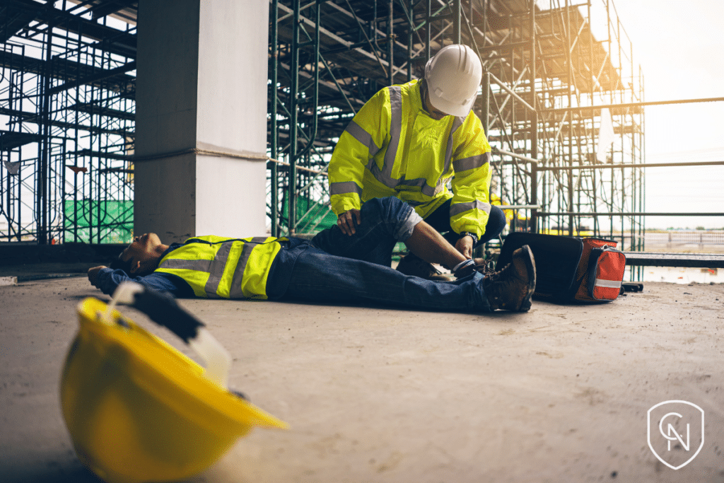 A safety officer provides first aid to an employee involved in an accident at a construction site.