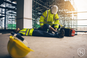 A safety officer provides first aid to an employee involved in an accident at a construction site.