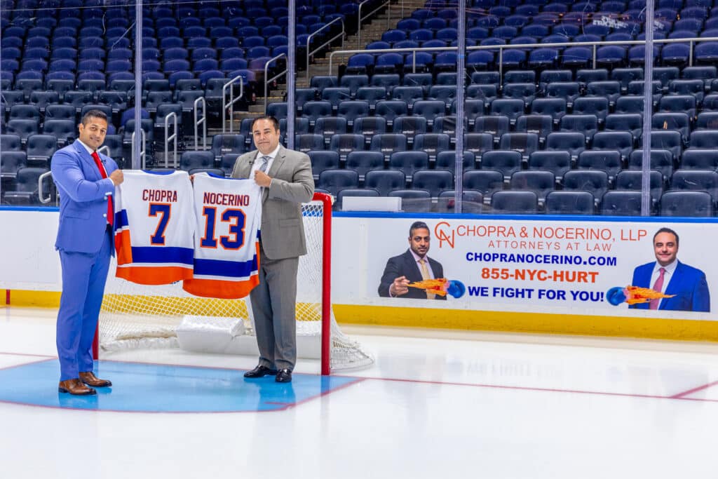 Long Island personal injury attorneys, Sameer Chopra and Alex Nocerino holding up NY Islander jerseys at UBS Arena