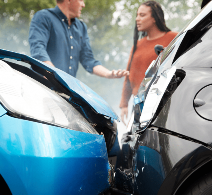 man and woman standing behind crash between a blue and black vehicle discussing who is at fault